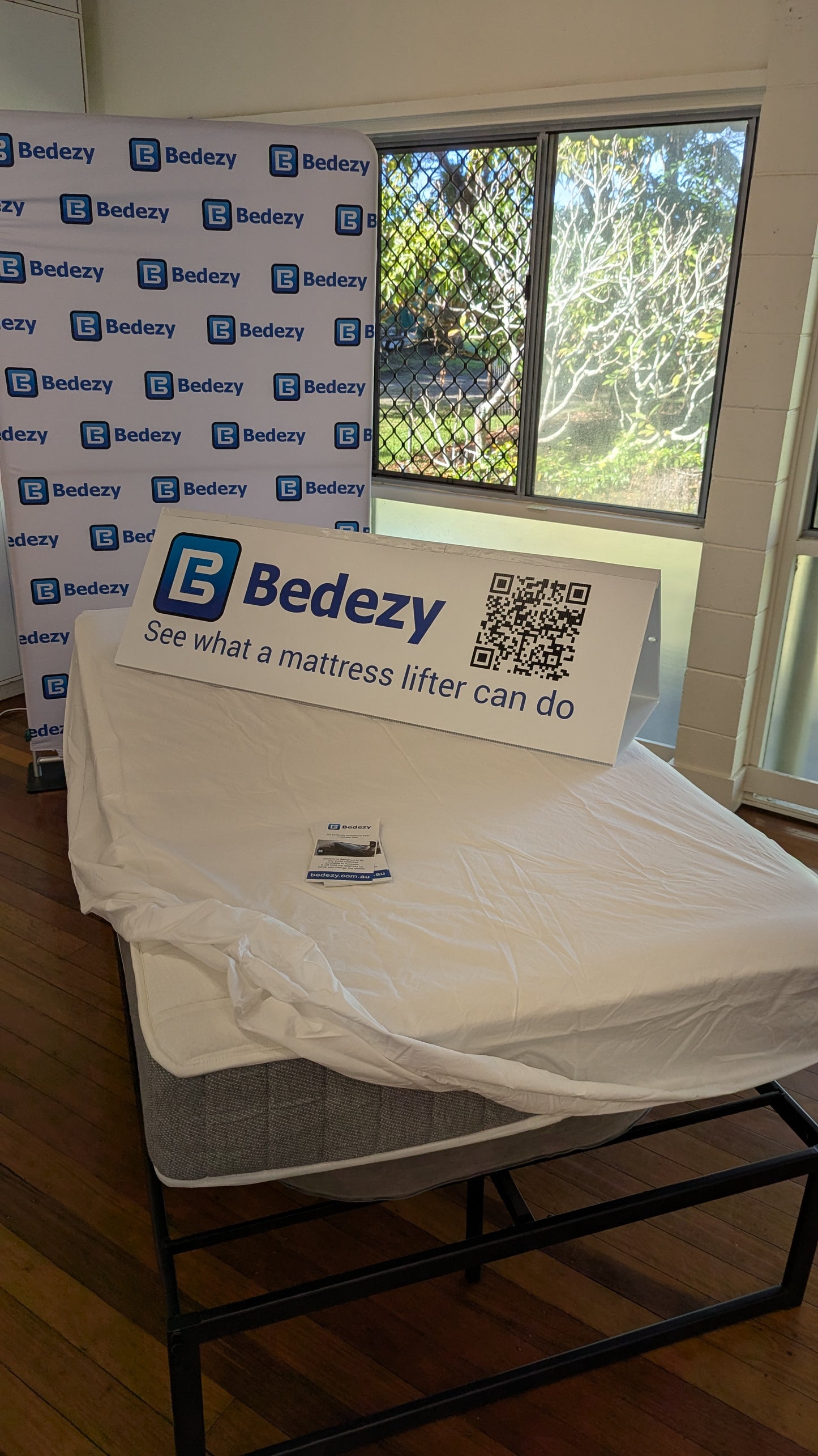 Mattress lifter with Bedezy branding and QR code on a wooden floor.